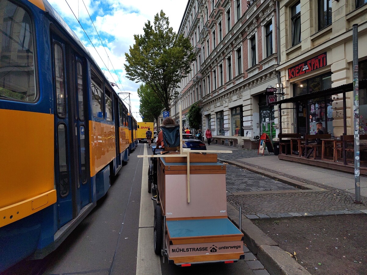 Lastenrad fährt voll bepackt neben einer Straßenbahn.