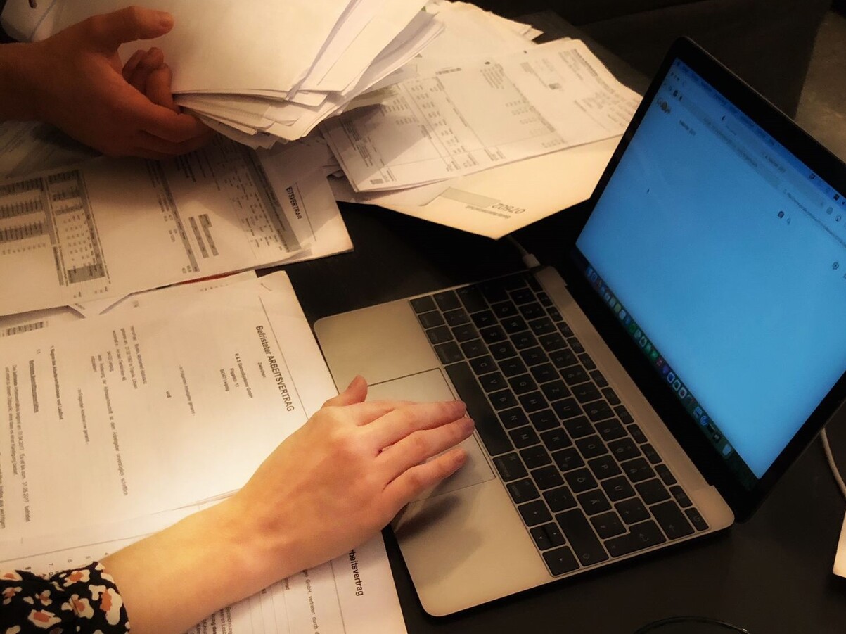 Viele Dokumente, zwei Hände und ein PC.